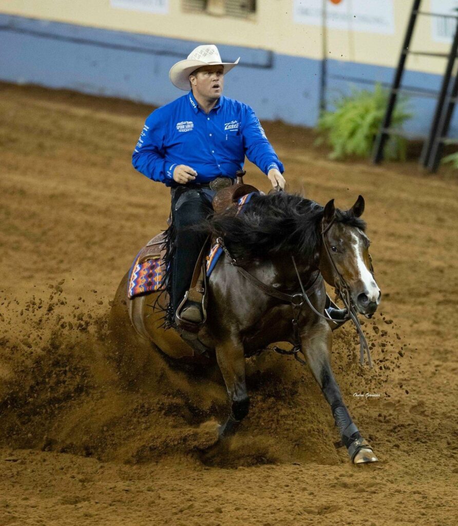 A Man in a Blue Shirt Riding a Horse in an Arena, Showcasing Equestrian Skills and Horsemanship.